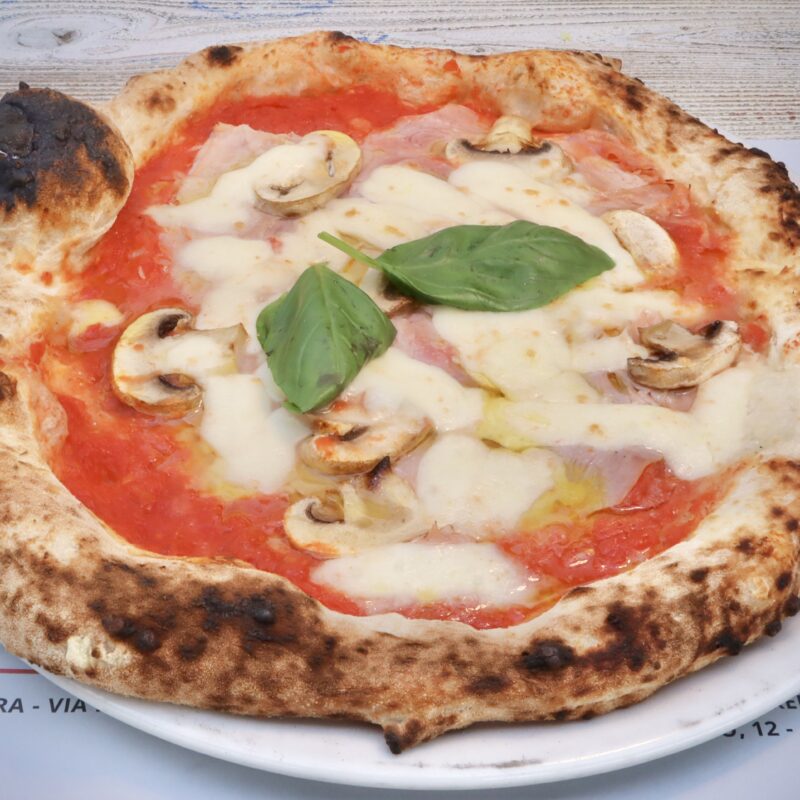 Pizza rossa con S.Marzano DOP, Fior di latte Lat- teria Sorrentina, Cotto, Funghi, basilico, olio pugliese